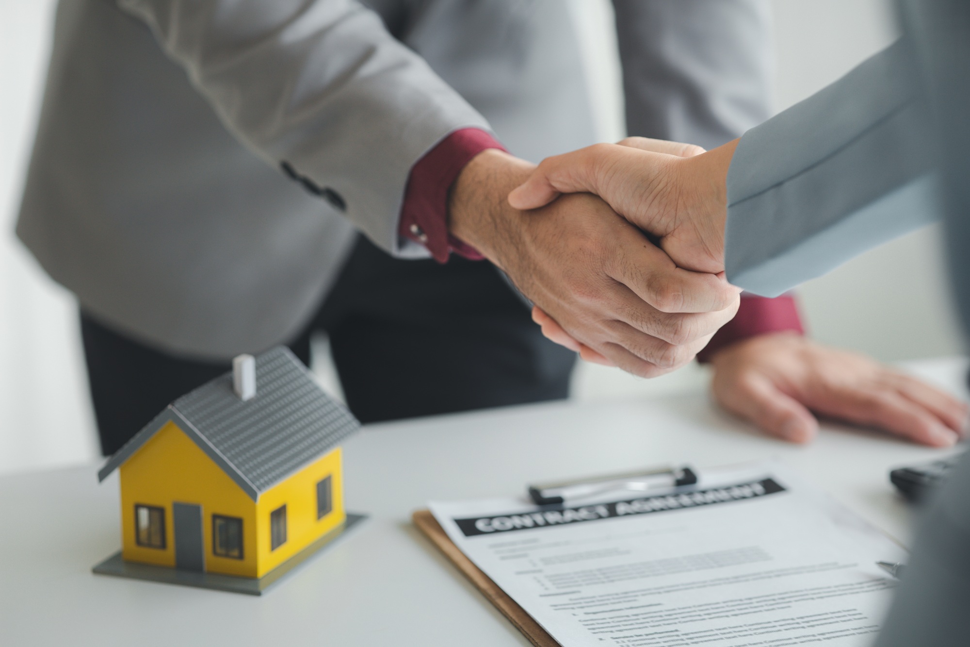 Housing estate agents shake hands with customers after a deal is completed.